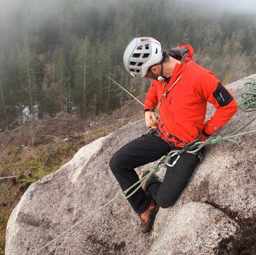 Rock climbers swapping gear at belay anchor